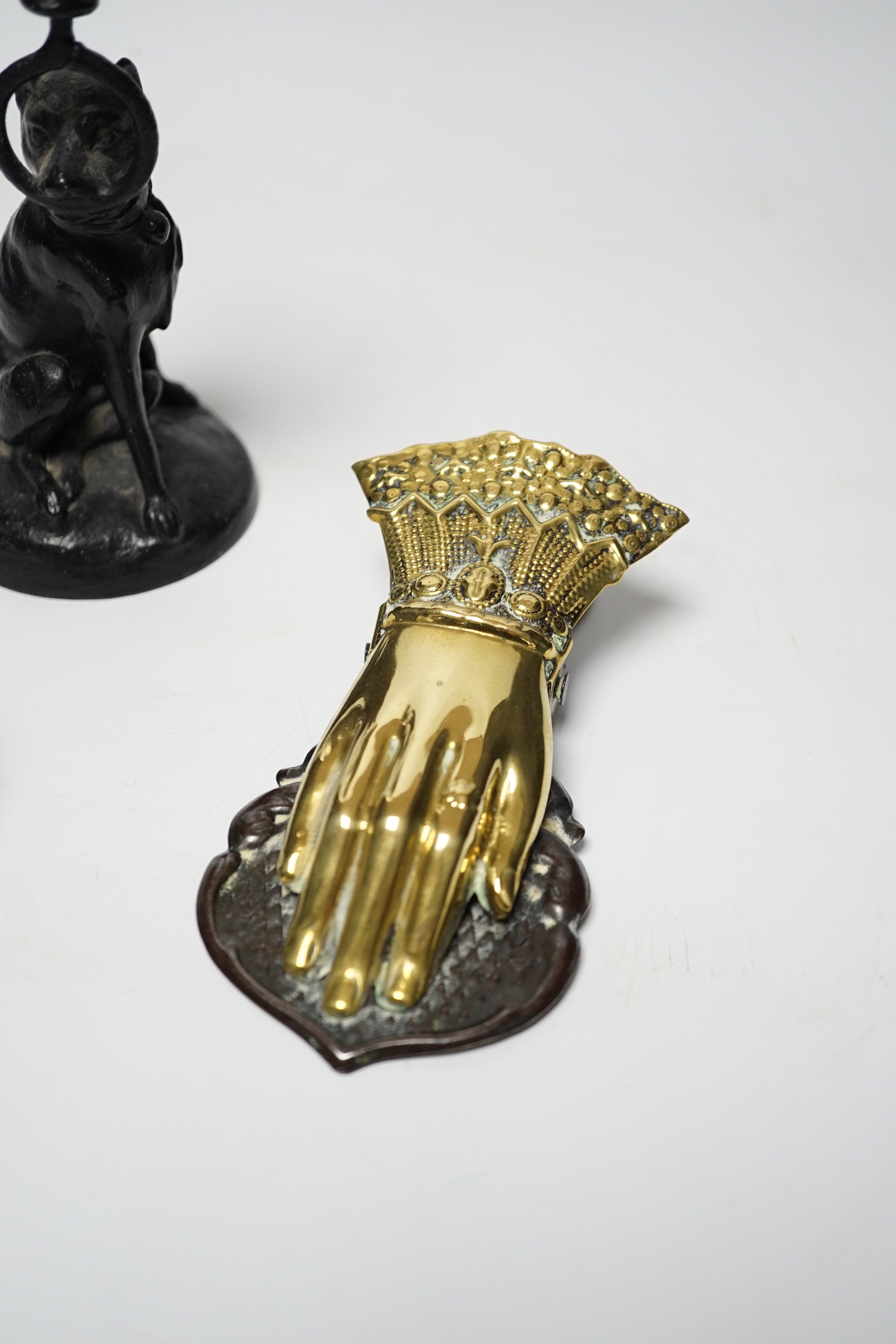 A Victorian brass hand paper clip, a small bronze tribal head and novelty dog candlestick, tallest 15cm high
